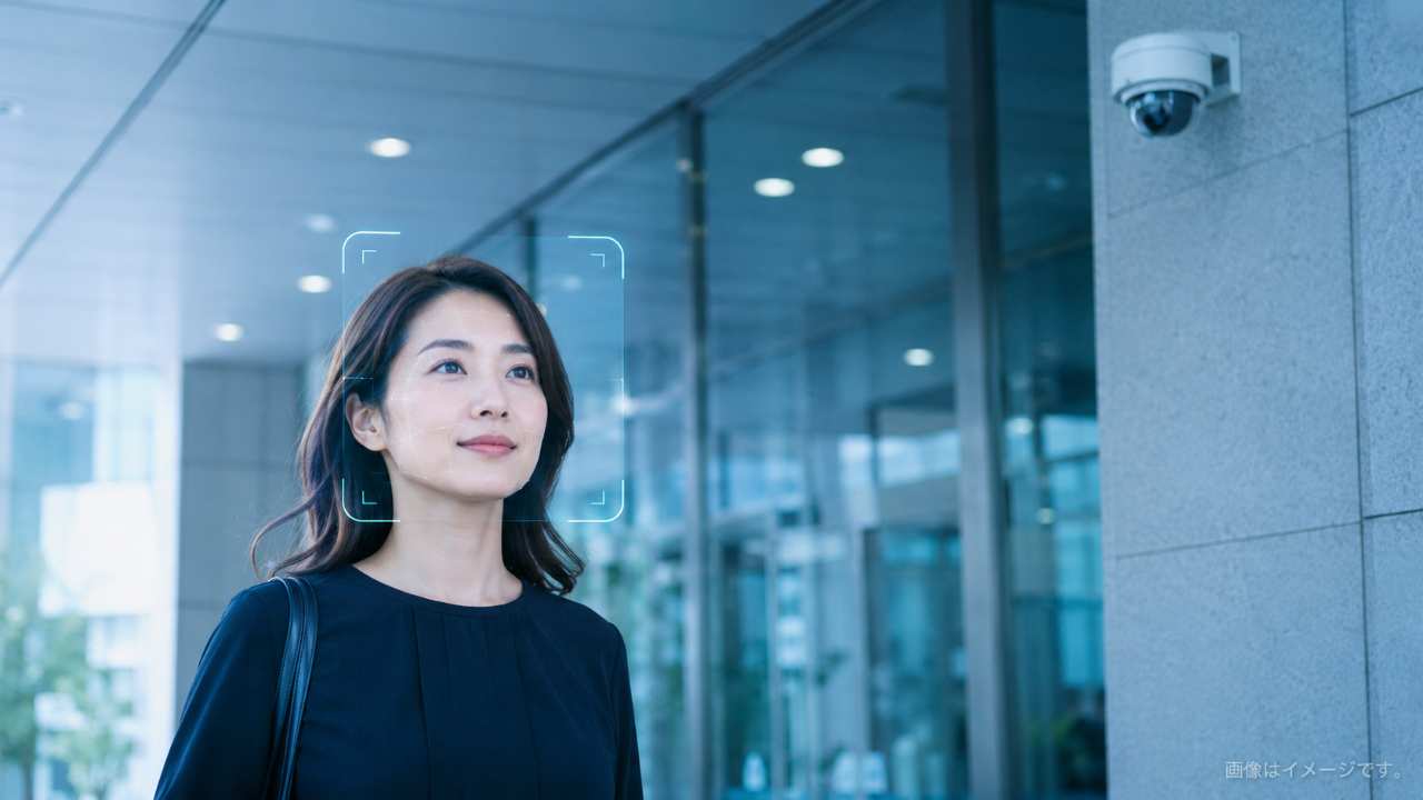 清潔感のあるオフィスビルまたは商業施設の入口に、防犯カメラが自然に設置されており、顔認証をイメージ